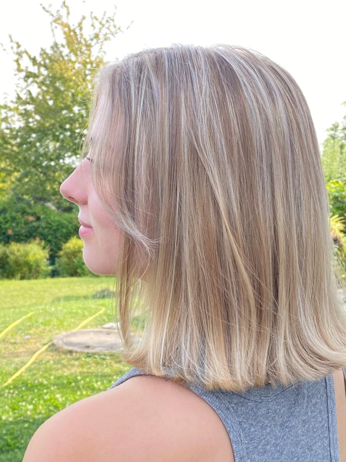 Schulterlanges glattes Haar mit hellen Strähnen in der Seitenansicht im Freien