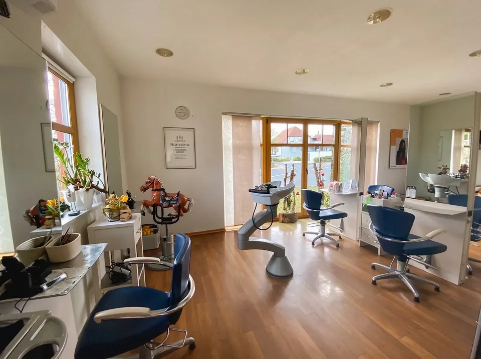 Salon mit blauen Frisierstühlen, Spiegeln und Holzfußboden
